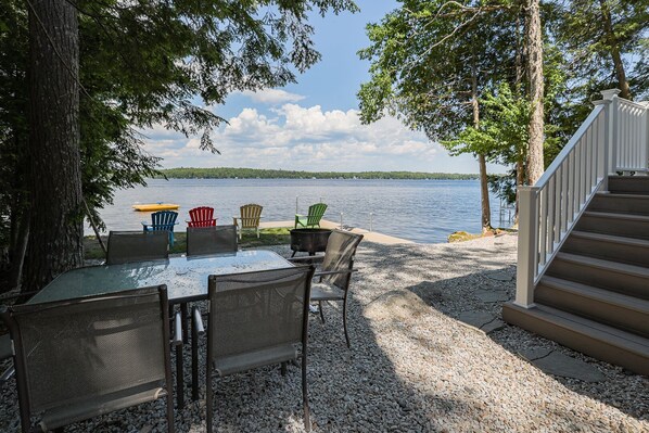 Un espace extérieur aménagé au bord du lac, avec une table, des chaises et un barbecue.