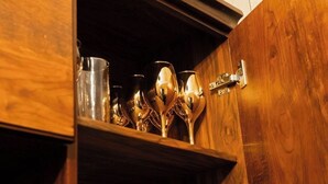 Ein Holzkabinett mit einer Ablage, auf der eine weiße Schüssel, ein Glas und mehrere Metalllöffel stehen.