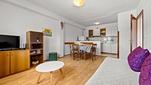 Ein kompakter Wohnbereich mit Fernseher, Holzmöbeln, Essplatz und Küche.