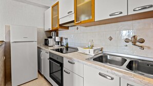 Eine Küche mit weißen Schränken, einer Edelstahlspüle, einer Mikrowelle und einem Kühlschrank.