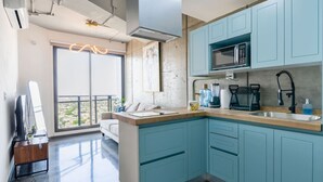 Une cuisine moderne avec des armoires de couleur turquoise, un four à micro-ondes et une machine à café.