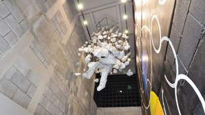 Un escalier étroit orné d’une sculpture décorative représentant une figure blanche, le tout étant entouré de lampes suspendues.