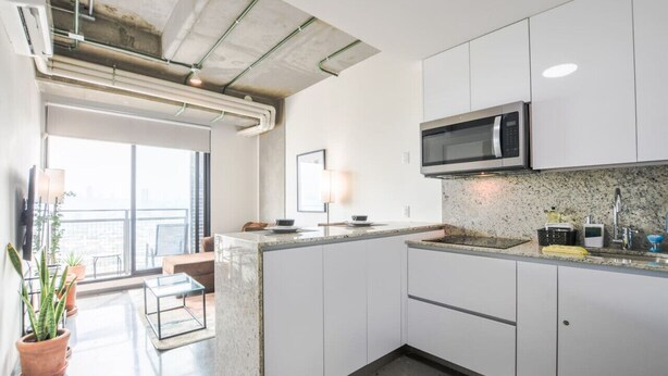 A modern kitchen with white cabinets, a built-in microwave, and a granite countertop.