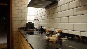 Een moderne keuken met witte metro betegeling, een zwart aanrecht en een Bosch koffiezetapparaat.