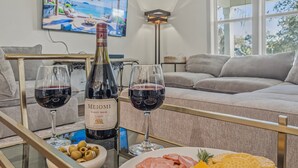 Zona de menjador amb una ampolla de Meomi Pinot Noir, dues copes de vi, un plat de formatge, galetes i olives.