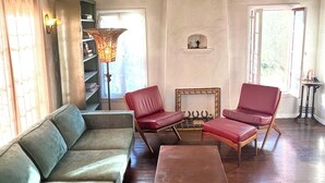 Ein Wohnzimmer mit einem grünen Sofa, zwei roten Sesseln, einem Holztisch und einer Stehlampe.