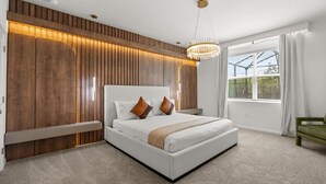 Un dormitorio moderno con una cama grande, paneles de madera, un candelabro y vistas a través del ventanal.