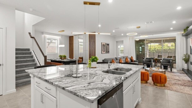 Una cocina moderna con una isla central, electrodomésticos integrados y una zona de comedor con sofá y sillas.