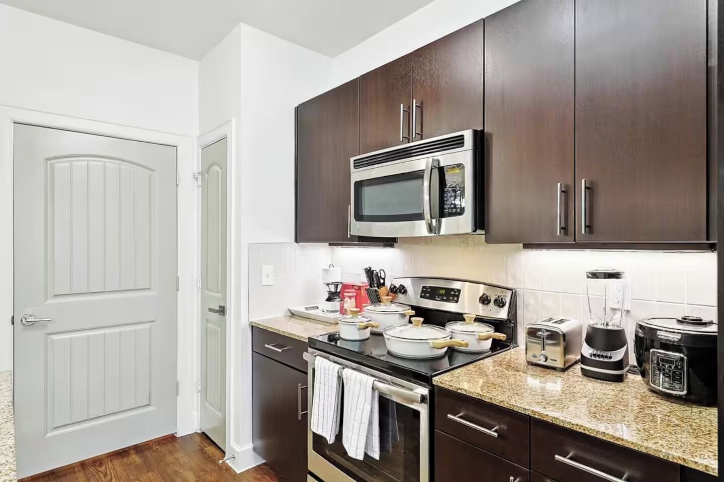 Una cocina moderna con armarios de madera oscura, electrodomésticos de acero inoxidable y encimera de granito.