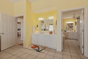 A bathroom with a large mirror, a sink, and a toilet. There are two doors leading to other rooms. - Casa Bonita Surfside (Freeport)