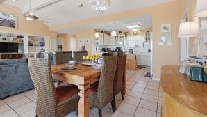 A spacious kitchen with modern appliances, a dining area with a wooden table and chairs, and a living room with a sofa and a television. - Casa Bonita Surfside (Freeport)
