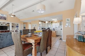 A spacious kitchen with modern appliances, a dining area with a wooden table and chairs, and a living room with a sofa and a television. - Casa Bonita Surfside (Freeport)