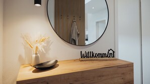 Ein hölzerner Empfangstresen mit einer schwarzen Maus, einer weißen Vase mit Trockenpflanzen und einem Willkommensschild.