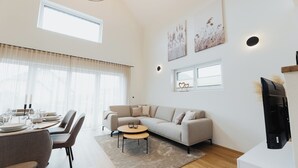 Ein modernes Wohnzimmer mit Sofa, Couchtisch und Essbereich.