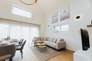 A modern living room with a sofa, coffee table, and dining area set up.