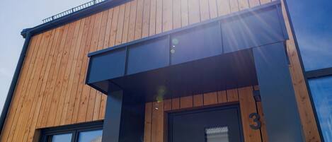 Un edificio moderno con fachada de madera y puerta de entrada con marco negro.