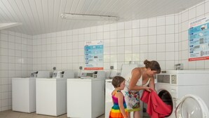 Une laverie équipée de plusieurs machines à laver et affichant un panneau avec des instructions.