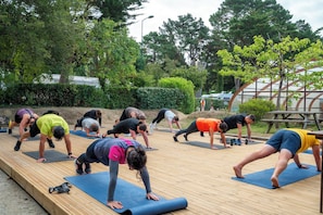 Un groupe de personnes pratiquant le yoga sur des tapis à l’extérieur, dans un parc.