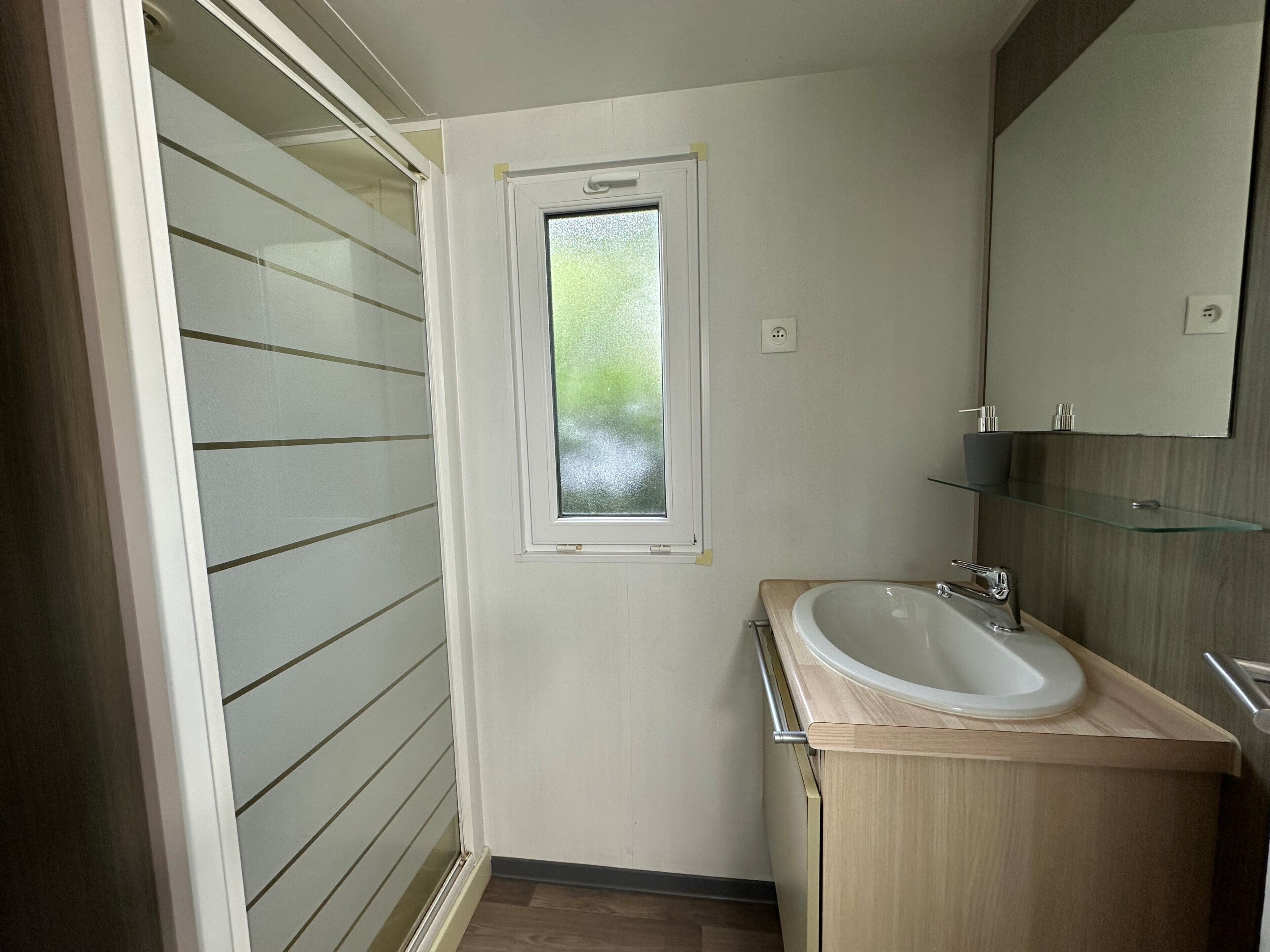 A bathroom with a window, a sink, and a mirror.
