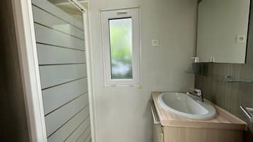 A bathroom with a window, a sink, and a mirror.