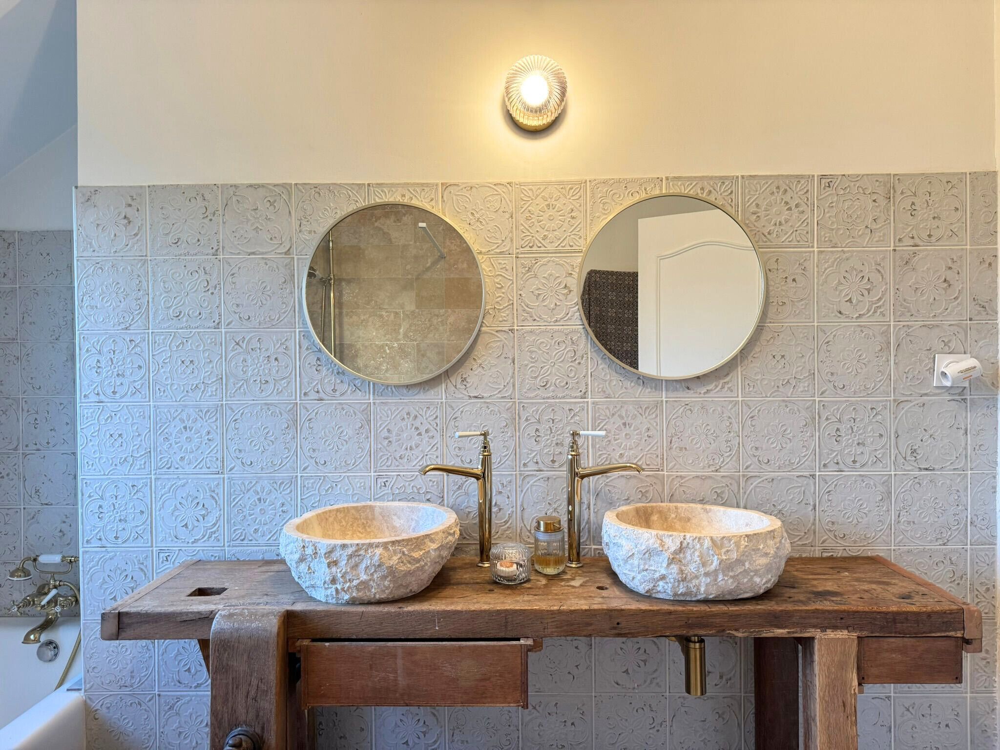 A bathroom with two stone sinks, a wooden vanity, and a round mirror above each sink.