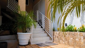 A staircase with white railings, a potted plant, and a welcome mat at the bottom. - Comfortable 1-bedroom Sweet Home. (Kingston 19)