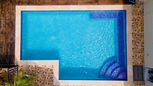 A rectangular swimming pool with a mosaic tile border and a 'WELCOME' sign. - Comfortable 1-bedroom Sweet Home. (Kingston 19)