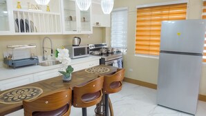 A modern kitchen with white cabinets, stainless steel appliances, and a wooden dining table with chairs. - Comfortable 1-bedroom Sweet Home. (Kingston 19)