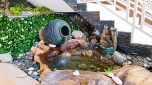 A small outdoor water feature with a rustic design, including a wooden structure and a large pot. - Comfortable 1-bedroom Sweet Home. (Kingston 19)