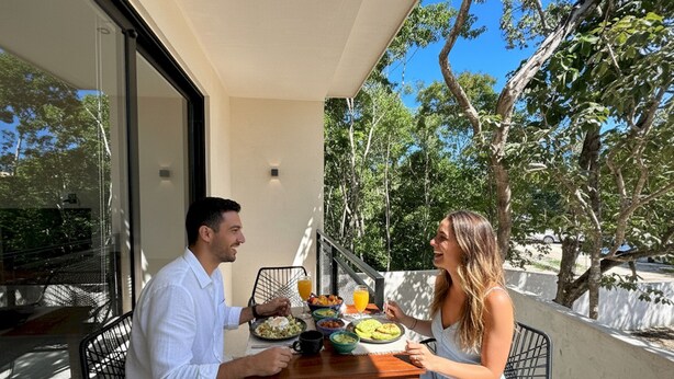 A couple dining at an outdoor table with a view of trees and a clear sky. - Pool Private Balcony Studio in Tulum S15 (Tulum)