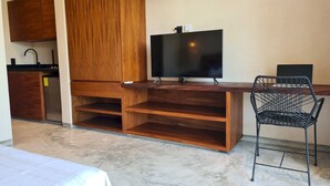 A compact living space with a wooden desk, a black chair, a television, and a small kitchenette. - Pool Private Balcony Studio in Tulum S15 (Tulum)