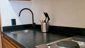 Una cocina con encimera negra, estufa de acero inoxidable y armarios de madera.