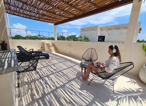 A covered outdoor seating area with chairs and a table, a staircase, and a building in the background. - Jungle View Studio S11 Private Jacuzzi Pool (Tulum)