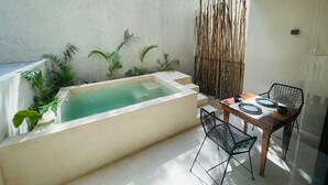 Un área de spa con un jacuzzi, una mesa con sillas y una pared de bambú.