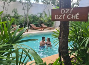Uma área de piscina com espreguiçadeiras e uma placa com a inscrição 'DZI DZI CHÉ'.