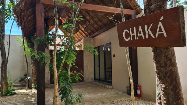 A wooden sign with the name "CHAKA" in a rustic setting with a thatched roof, stone pathway, and surrounding greenery. - Tulum Studio Jungle Pool S14 (Tulum)