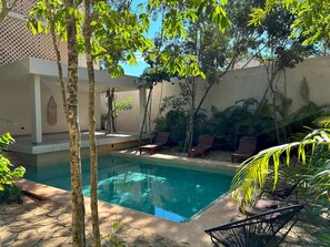 Uma área de piscina com espreguiçadeiras e um pergolado.