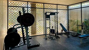 A gym with weightlifting equipment, a bench, and a window with a lattice pattern. - Jungle Escape Studio Quiet Cozy Gym Pool C5 (Tulum)