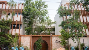 A building with a brick entrance, trees, and parked scooters. - Jungle Escape Studio Quiet Cozy Gym Pool C5 (Tulum)