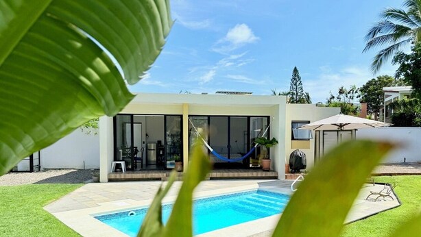 Una casa moderna con piscina, un'amaca e una zona relax sul patio.