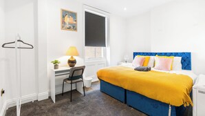 Un dormitorio con cama, escritorio, silla y ventana con persianas.