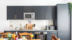 Una cocina moderna con armarios oscuros, microondas, tostadora y pileta.