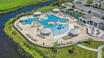 Eine Luftaufnahme eines Resorts mit einem zentralen Schwimmbecken, umgeben von Liegebereichen und einem kleinen Wasserpark.