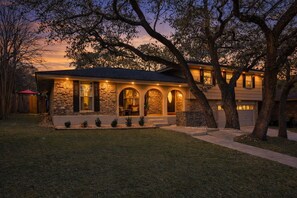 A two-story house with a stone facade, large windows, and a covered front porch. - 4BR w/ Pickleball Court, Heated Pool & Hot Tub (San Antonio)