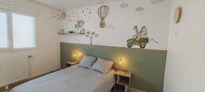 A bedroom with a bed, two bedside tables with lamps, a window, and wall decorations including a tree, animals, and a hot air balloon.