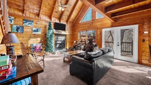 Ein gemütliches Blockhaus-Interieur mit Kamin, Holzwänden, einer Ledersofa und einem Weihnachtsbaum.