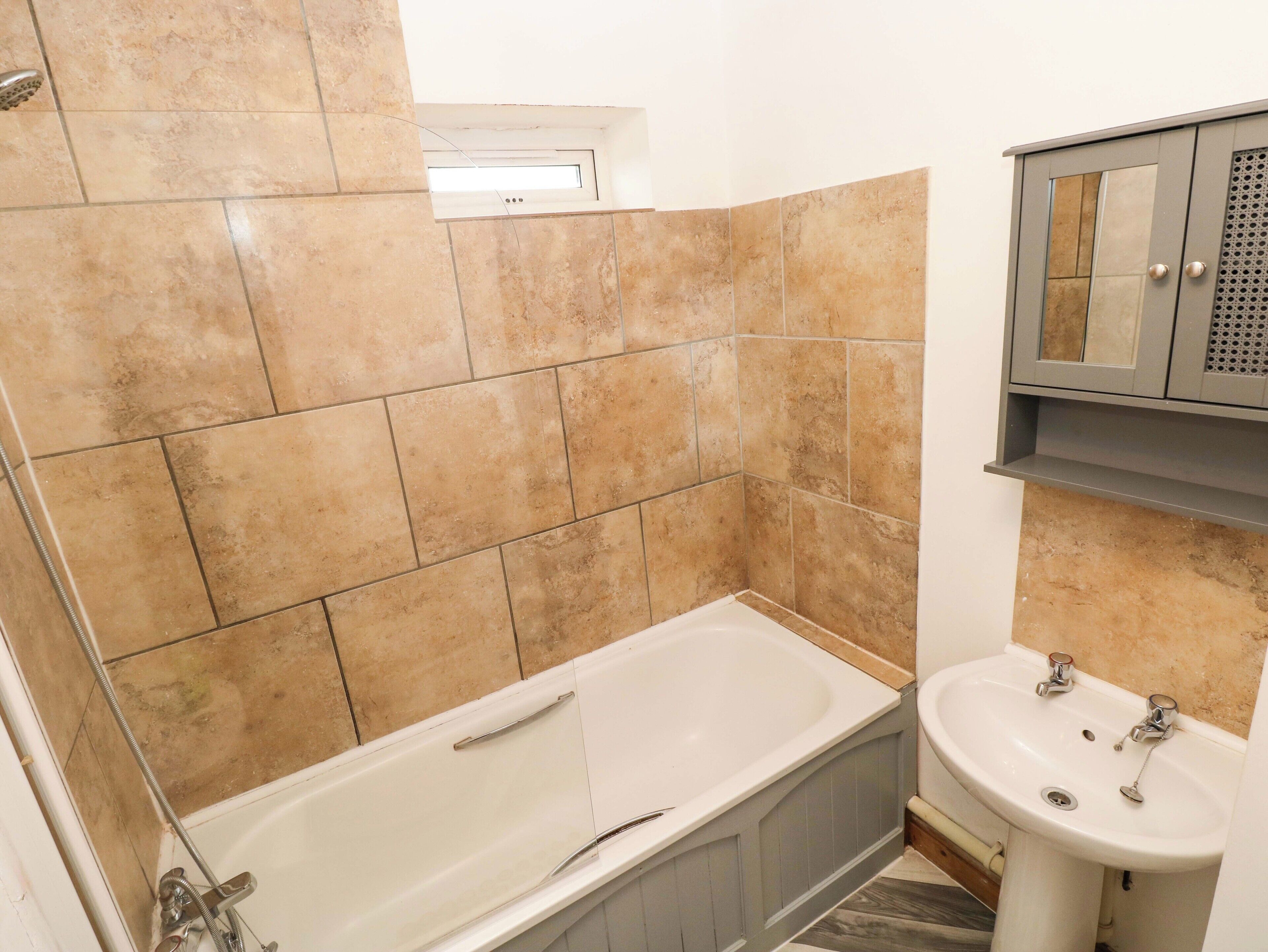 A bathroom with a bathtub, a sink, and a cabinet.