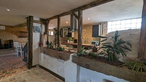 A rustic interior with exposed stone walls, a brick floor, and a kitchen area with modern appliances. - Charming country house with garden - 7 guests (Courtemaux)