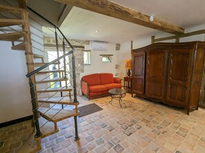Un escalier avec une rampe en bois, un canapé rouge, un meuble en bois et une petite table avec une lampe.