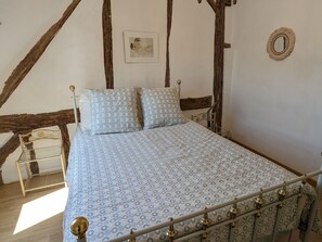 Une chambre à coucher avec un lit, des poutres en bois, une petite table et un miroir fixé au mur.